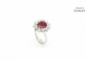 Ring with central ruby of 3.12ct oval cut and a border of diamonds.