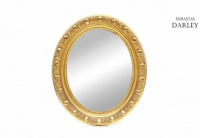 Espejo oval con marco de madera dorada.