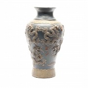 Jarrón de cerámica china con dragones en relieve y fondo azul.