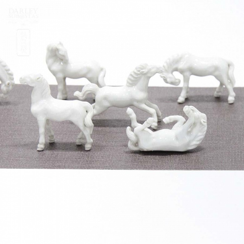 Siete caballos de porcelana blanca en miniatura.