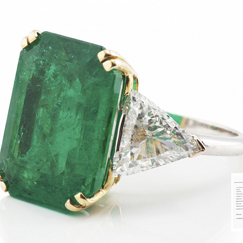 Ring with a large Colombian emerald of 11.19ct and triangle cut diamonds on both sides.