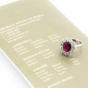 Ring with central ruby of 3.12ct oval cut and a border of diamonds.