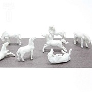 Seven miniature white porcelain horses.